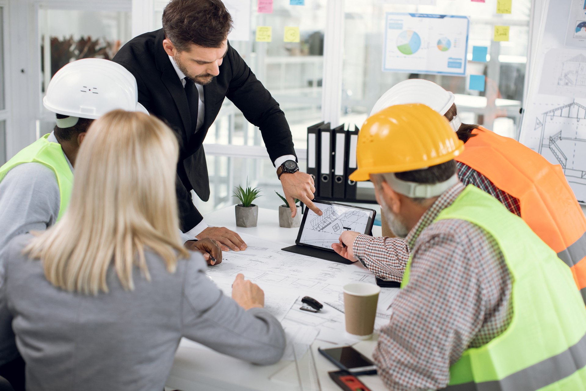 Multiracial team of engineers and male and female managers, brainstorming together over joint building project